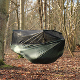 DD Superlight Frontline Hammock suspended in a forest, featuring a lightweight ripstop nylon design.